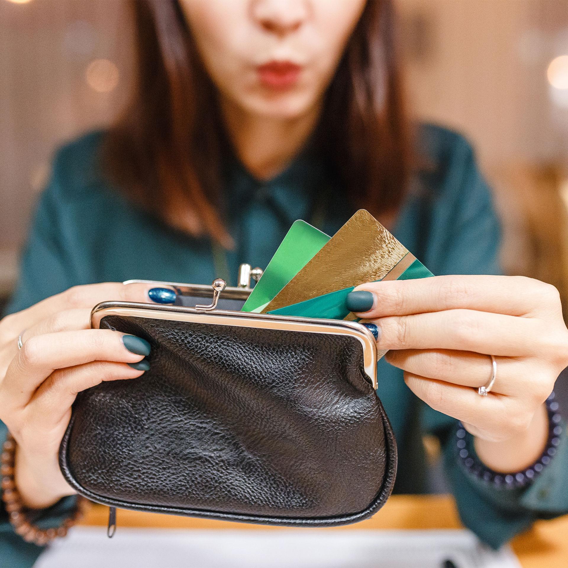 a woman pulls several cards out of her wallet and wonders if she should use her credit card for everything
